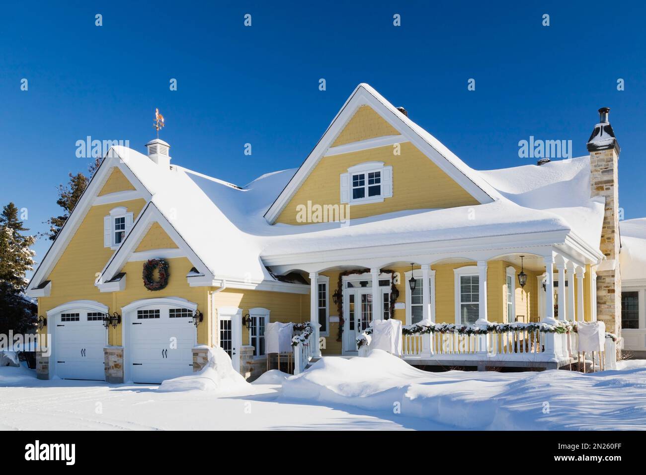 Yellow with white trim country cottage style house with Christmas decorations in winter. Stock Photo