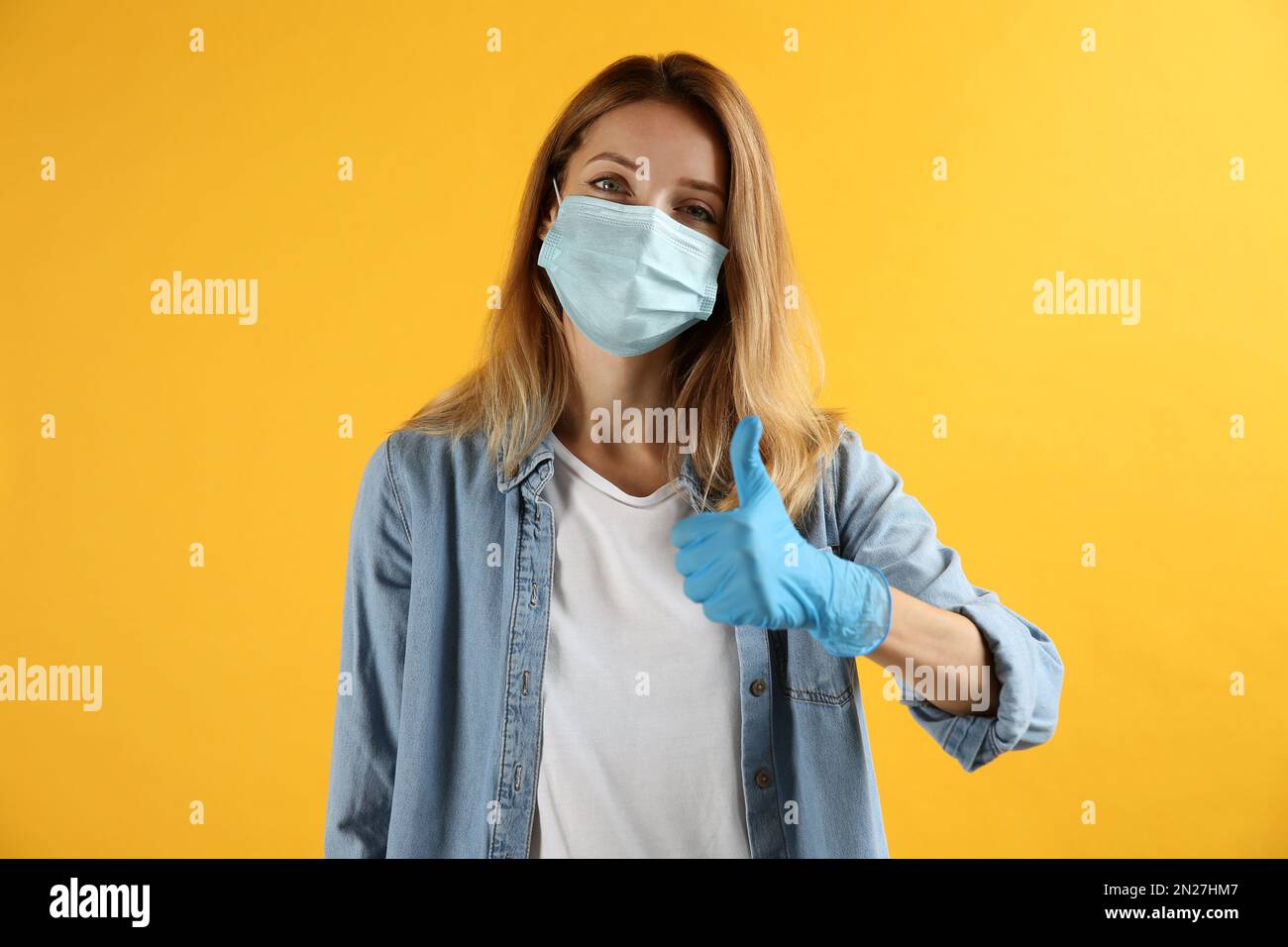 Young woman in medical gloves and protective mask showing thumb up on ...