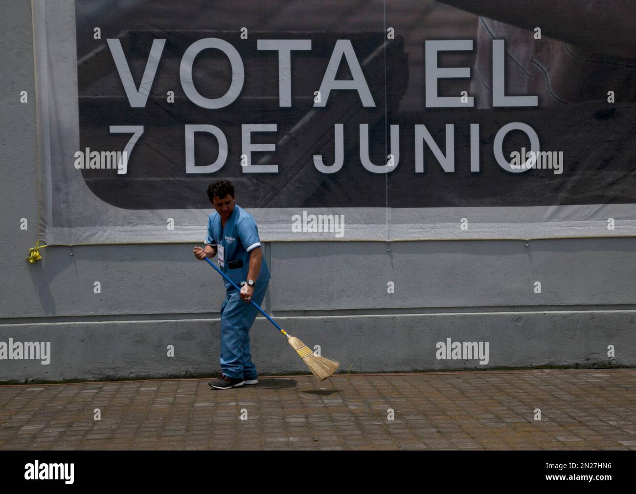 A worker sweeps the sidewalk, backdropped by banner with a message that