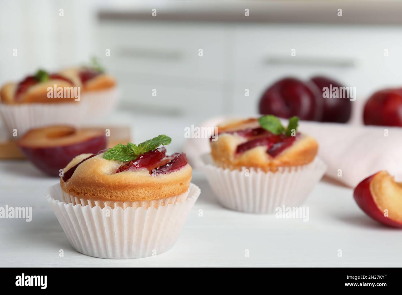 Delicious cupcakes with plums on white wooden table, closeup Stock