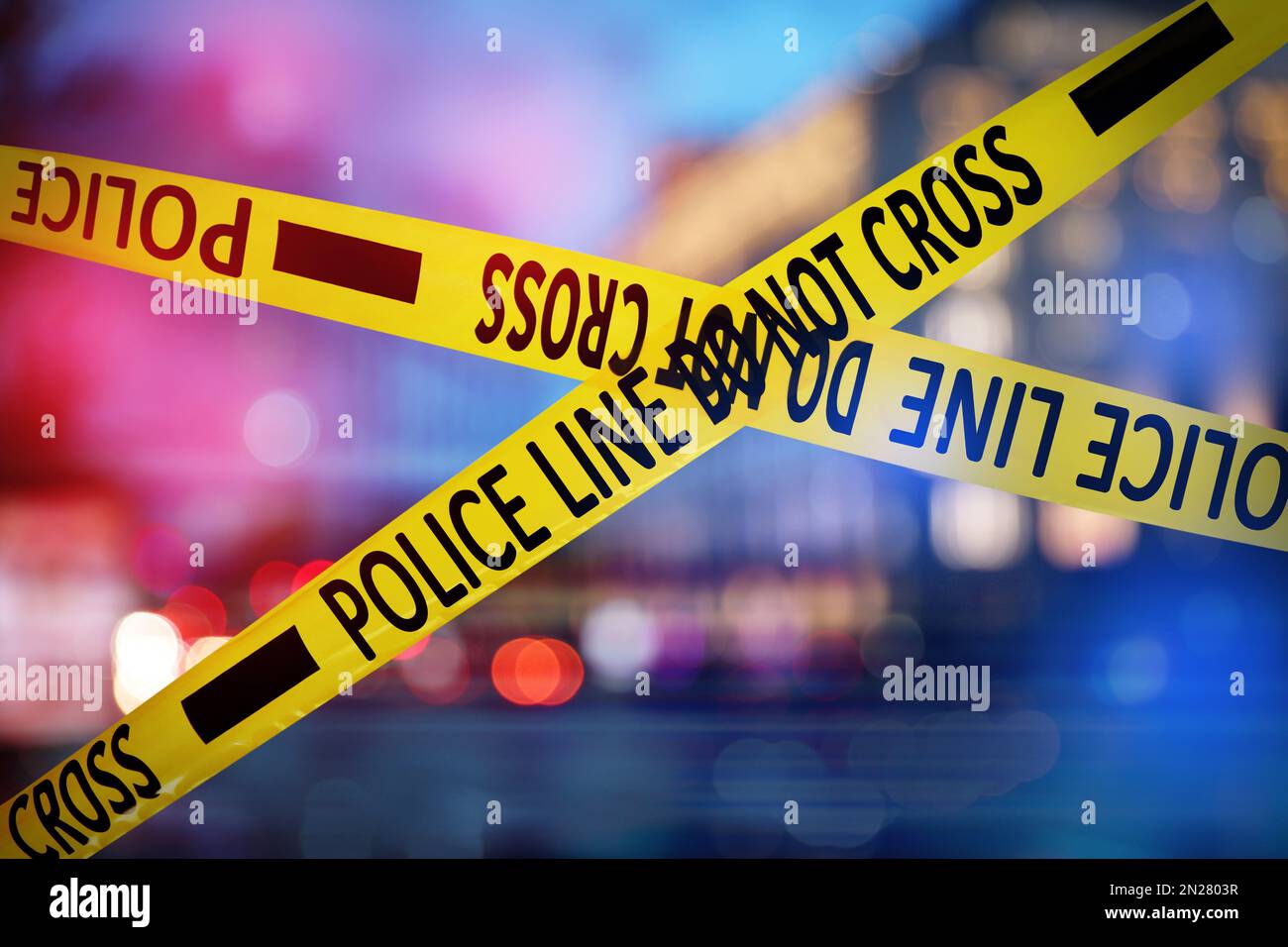 Yellow law enforcement tape isolating crime scene. Blurred view of city