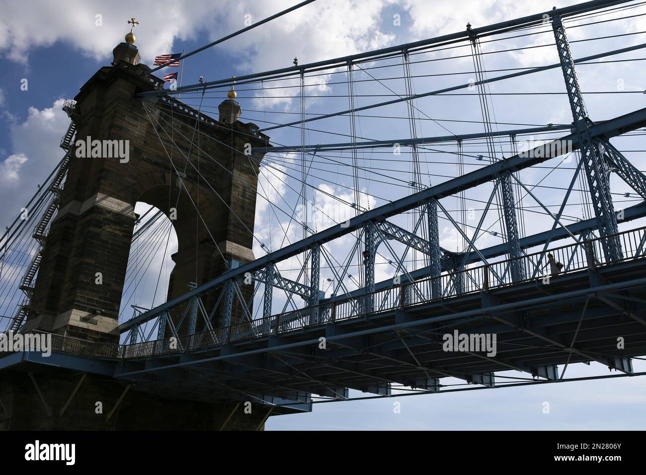 A pedestrian walks over the John A. Roebling Suspension Bridge towards ...