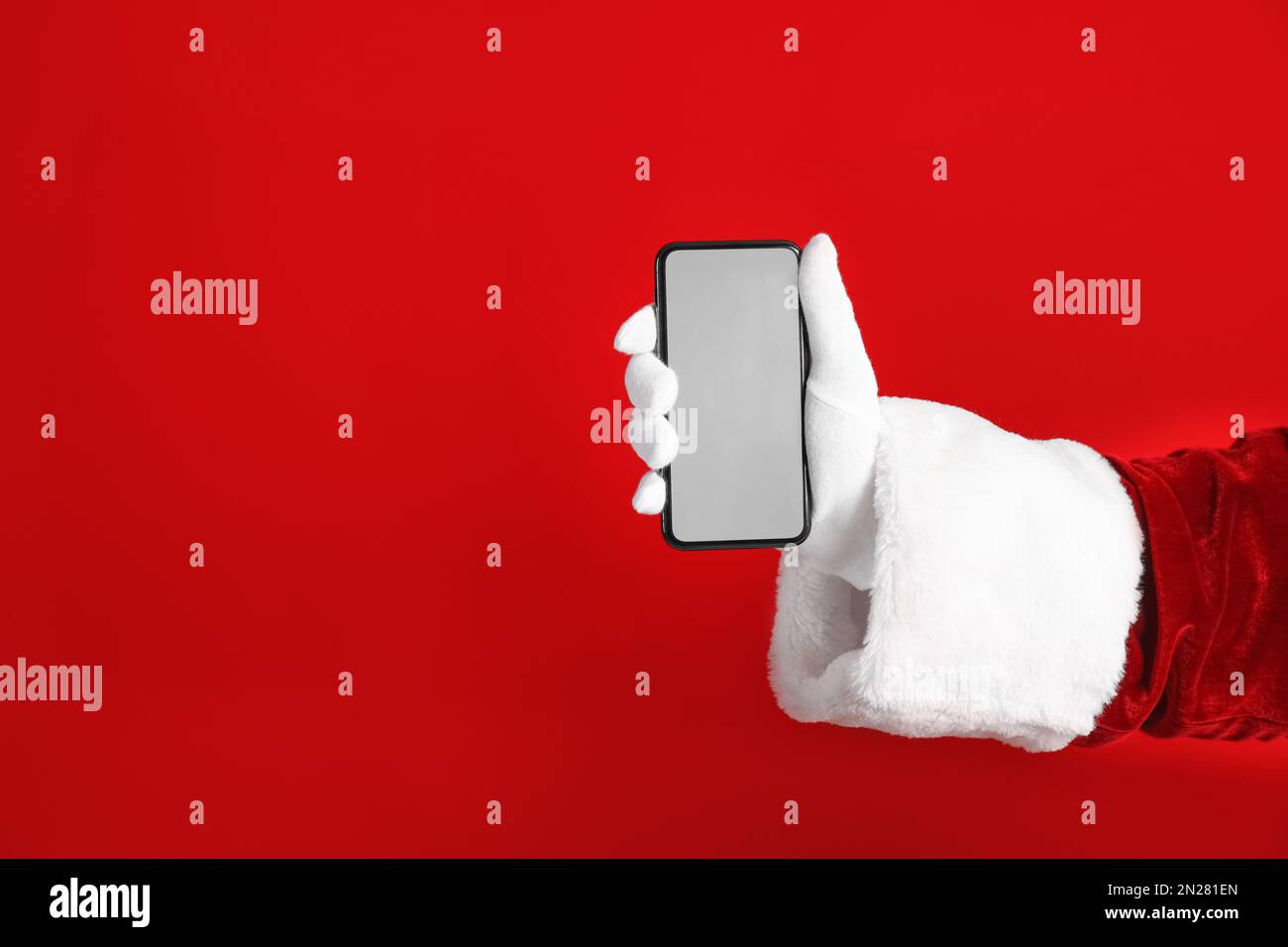 Santa holding modern mobile phone with blank screen on red background ...