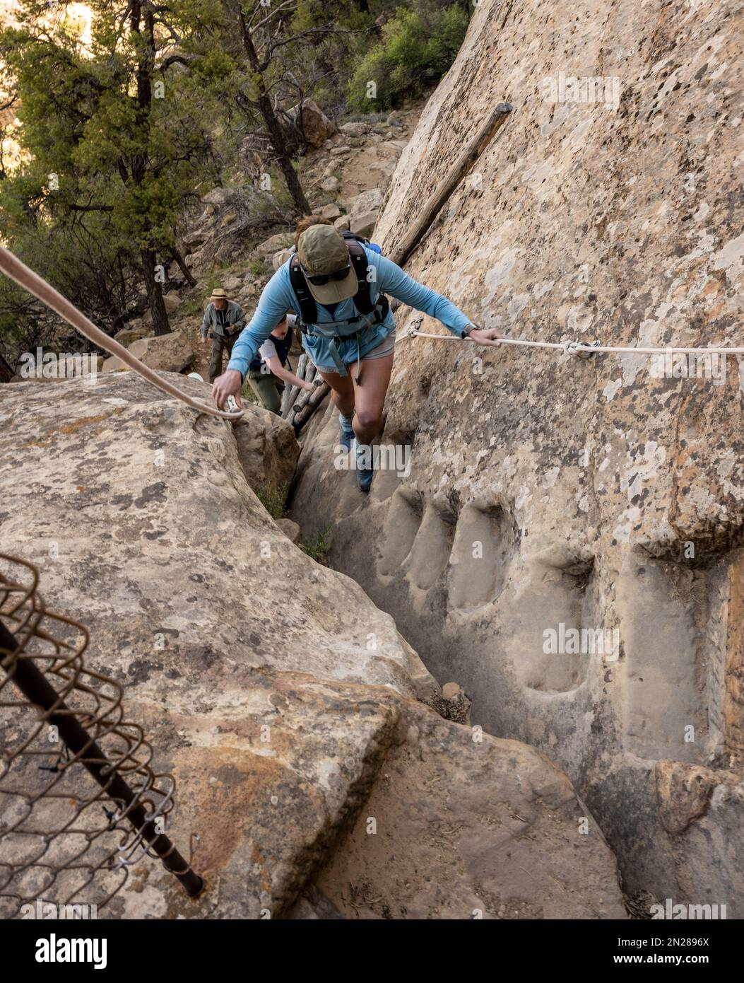 Woman Climbs Up Stone Steps Carved Out of Rock Cliff in Mesa Verde National Park Stock Photo