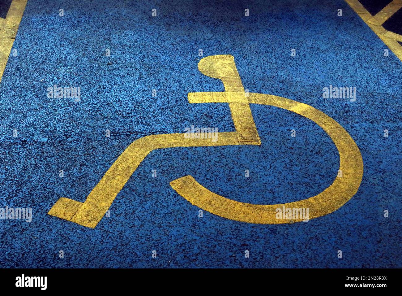 Textured surface on blue and yellow painted,disabled parking space NCP Stockport Stock Photo