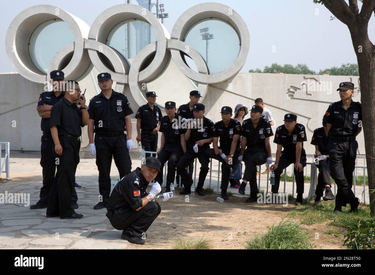 Chinese security guards rest in the shade of trees near Olympic rings ...