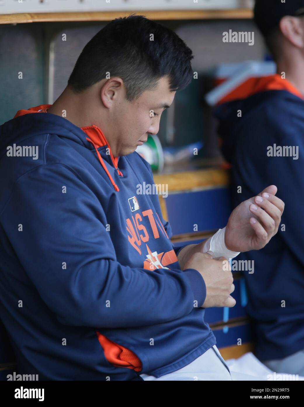 Houston Astros catcher Hank Conger wraps his wrist while sitting in the dugout during a baseball