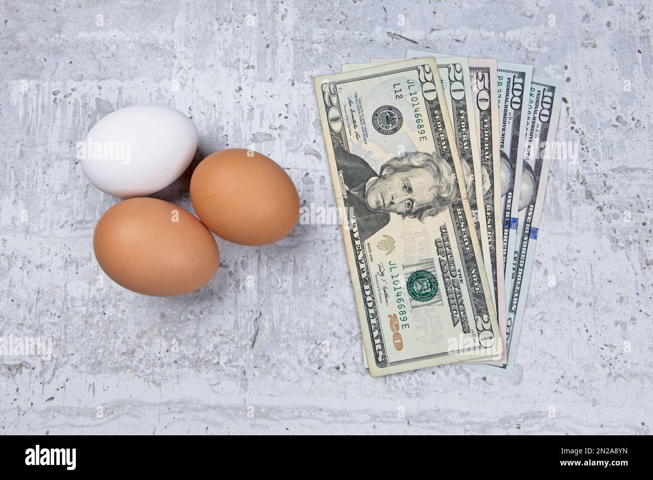 A conceptual flatlay photo of showing eggs and a fanned out stack of cash depicting the rising cost of eggs and food. Stock Photo