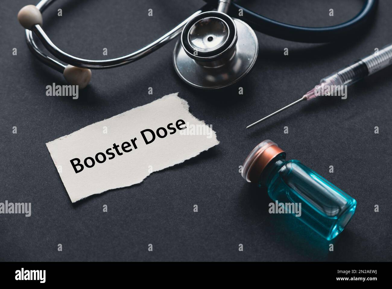 Selective focus of stethoscope. syringe, a bottle of vaccine and a piece of paper written with Booster Dose. Stock Photo