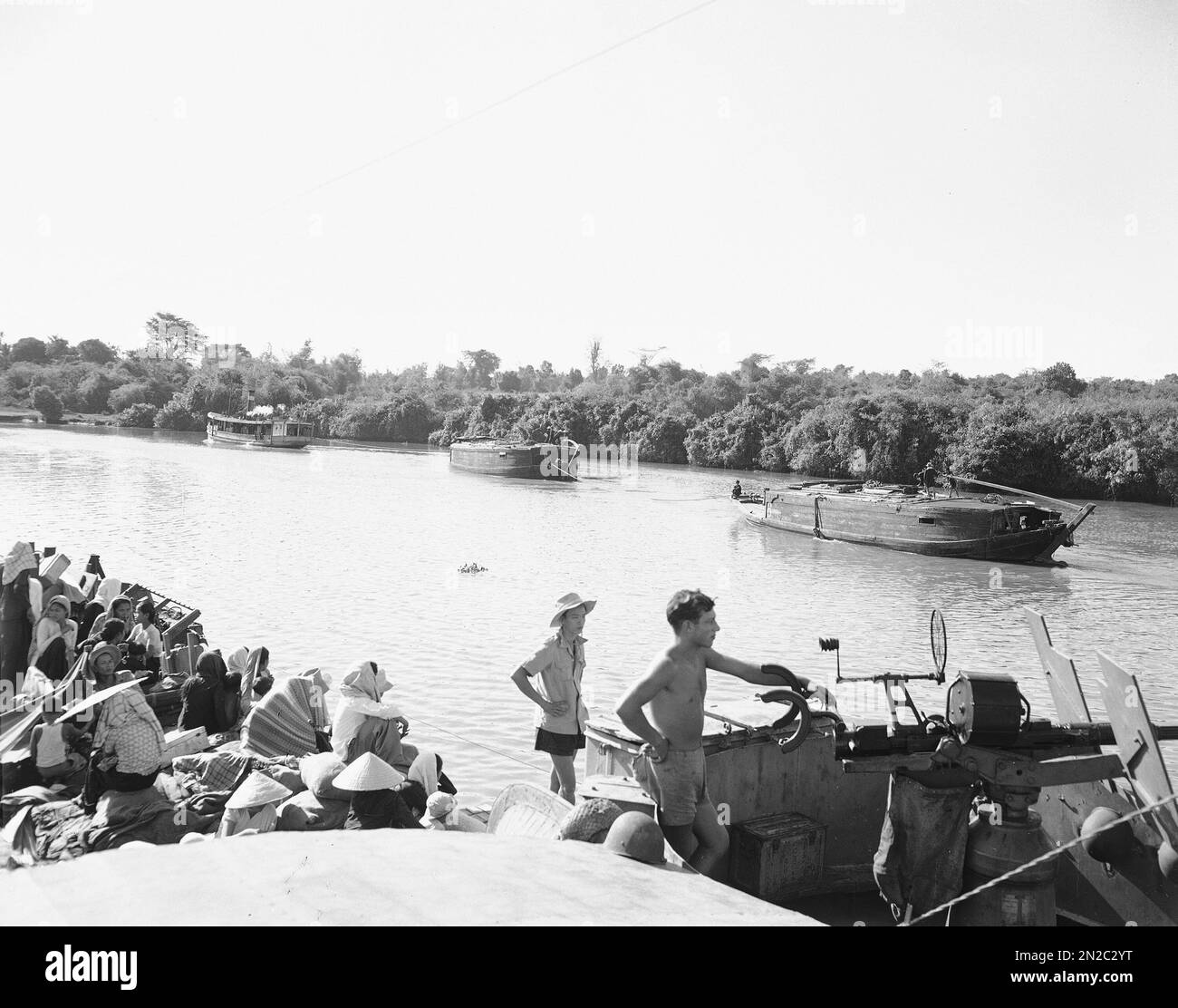 Michelin rubber convoy passes LCT somewhere in Vietnam, Feb. 12, 1951. Note  native soldiers, women, and children on forward deck. Andre LeBlois, Tours,  watches near 20mm gun. (AP Photo/Jean-Jacques Levy Stock Photo -