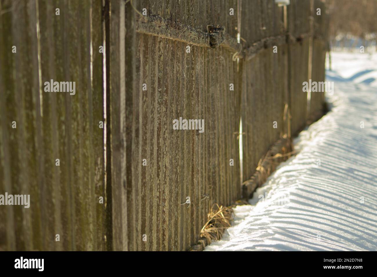 Fence made of wood in winter. Wooden fence in countryside. Territory of farm is in snow. Stock Photo