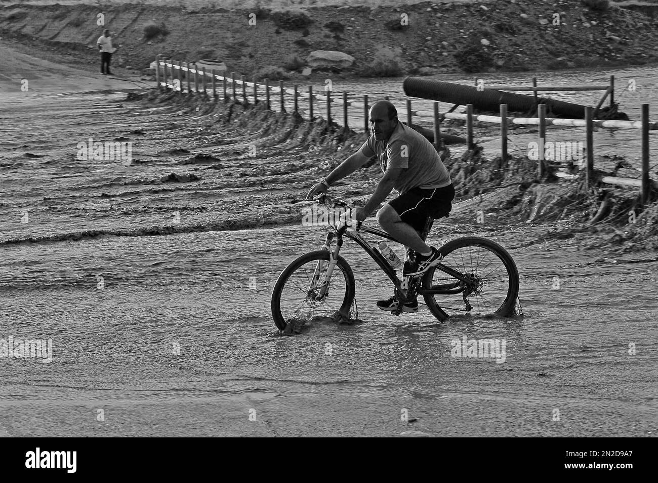 Man on bicycle on flooded bridge after heavy rain, Grima, Andalucia, Spain Stock Photo