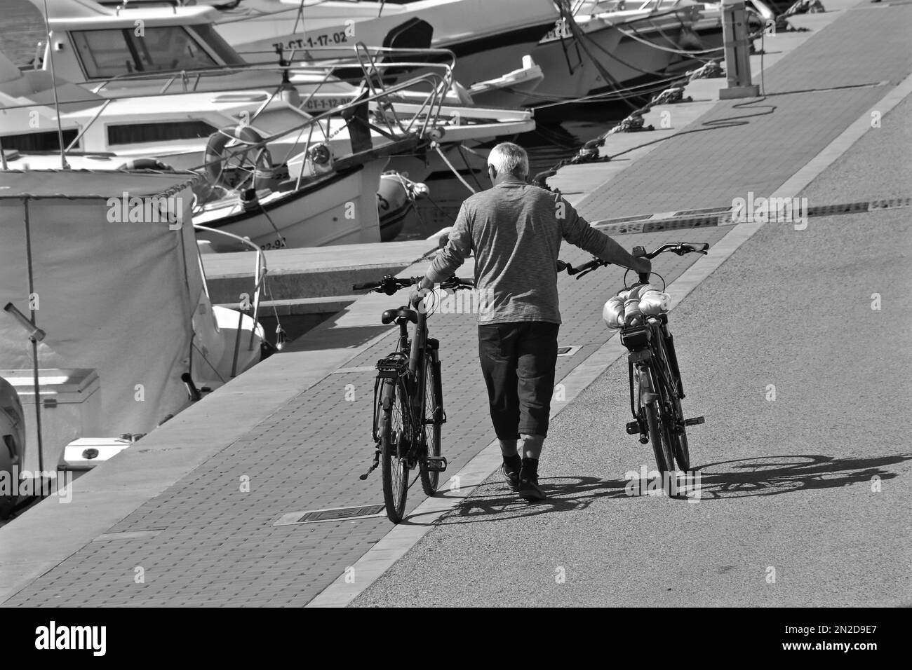 Man pushing two bicycles at port, Garrucha, Andalusia, Spain Stock Photo