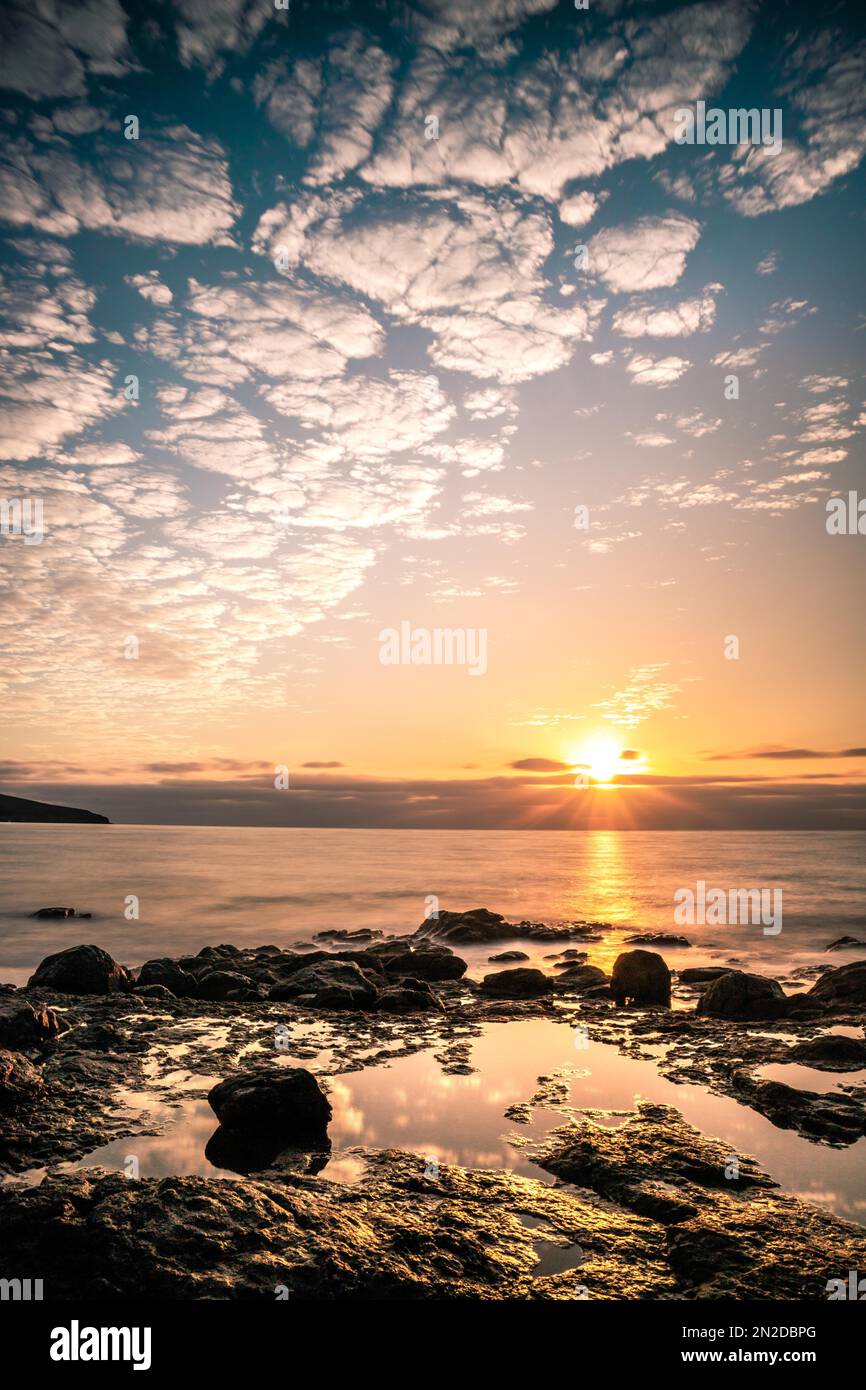 Sunrise, over the sea in a rocky bay, clouds, long exposure, backlight shot, volcanic rock, Fuerteventura, Canary Islands, Spain Stock Photo