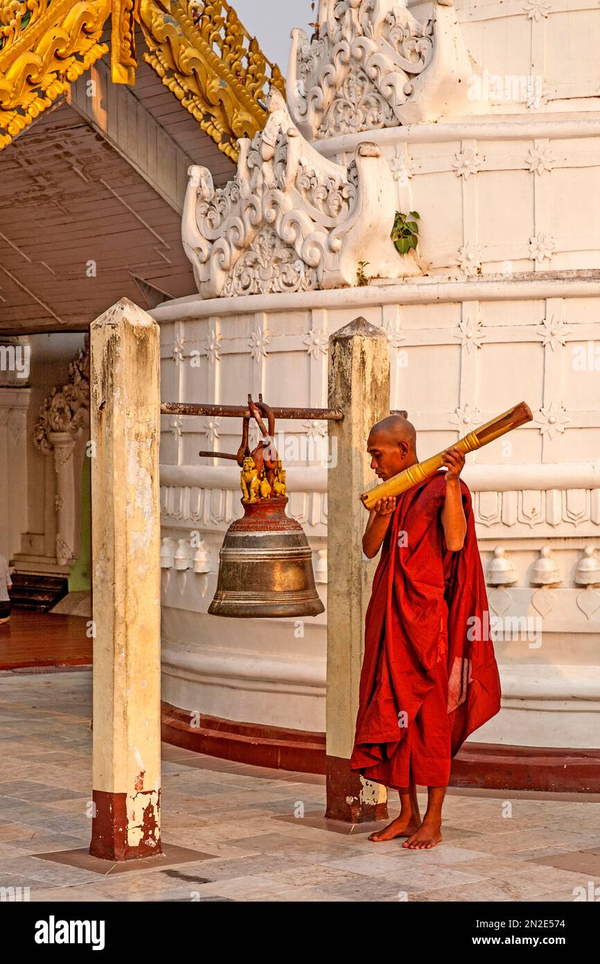Monk ritually strikes a bell, Shwedagon Pagoda, Yangoon, Myanmar ...