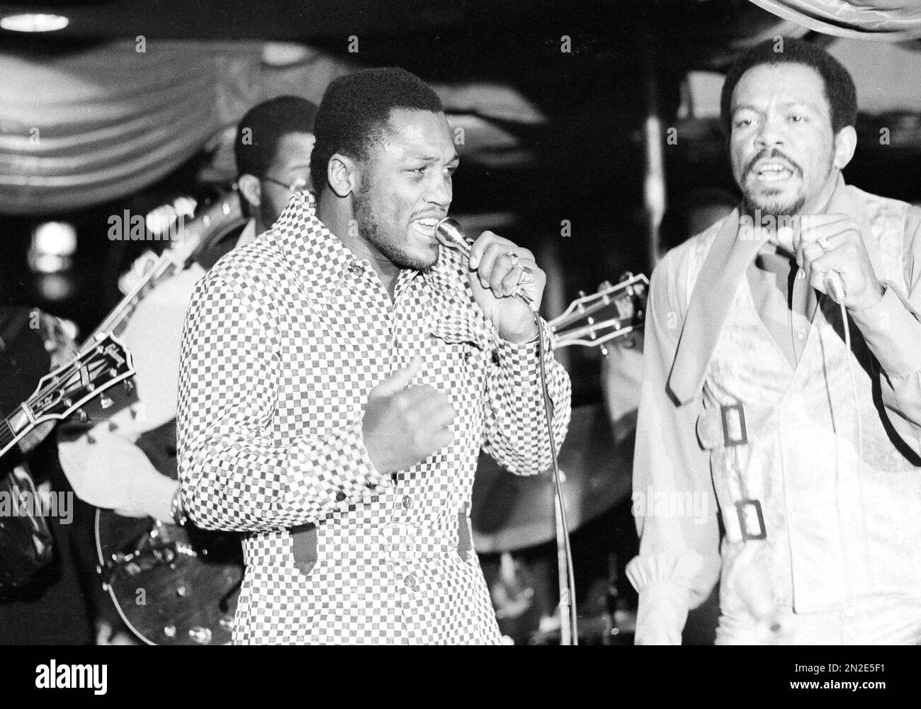 Heavyweight boxing champion Joe Frazier, left, belts out a tune as he