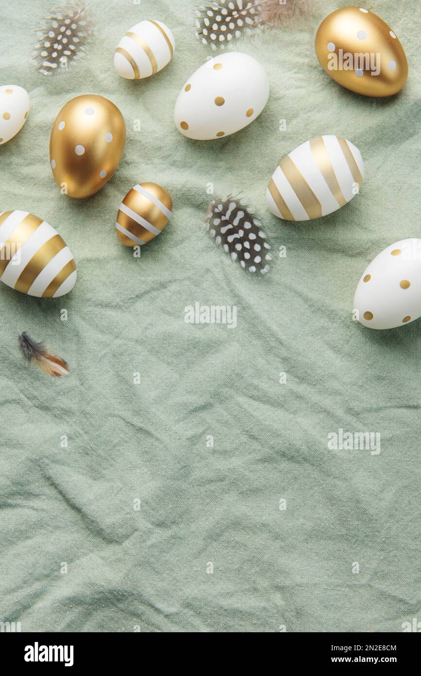 Easter eggs are painted with gold paint on a green linen background ...