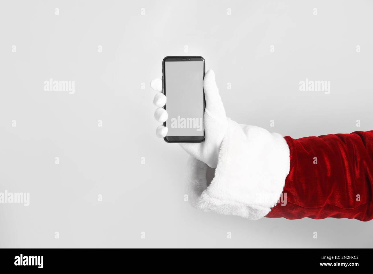 Santa holding modern mobile phone with blank screen on light grey ...