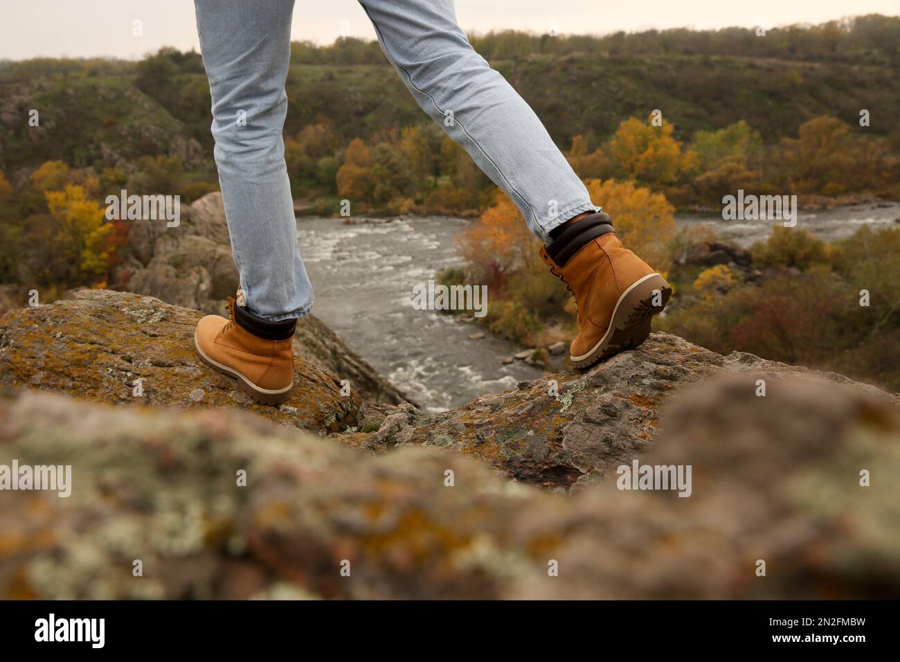 Man wearing stylish hiking boots on steep cliff, closeup Stock Photo