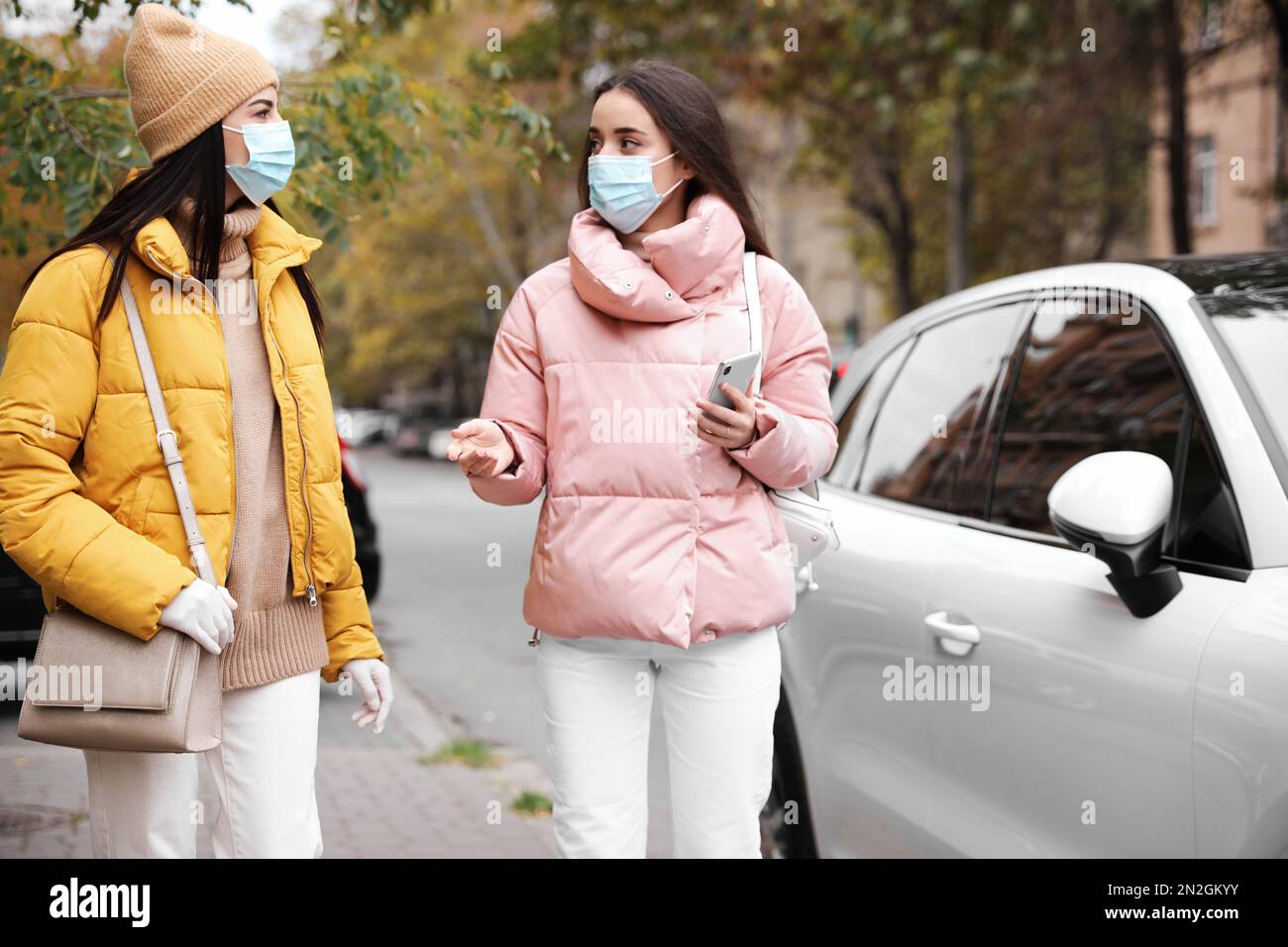 Young women in medical face masks walking outdoors. Personal protection ...