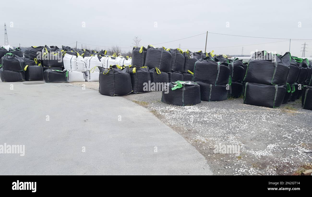 open warehouse of big black Stacking bulk cargo in jumbo bags store in