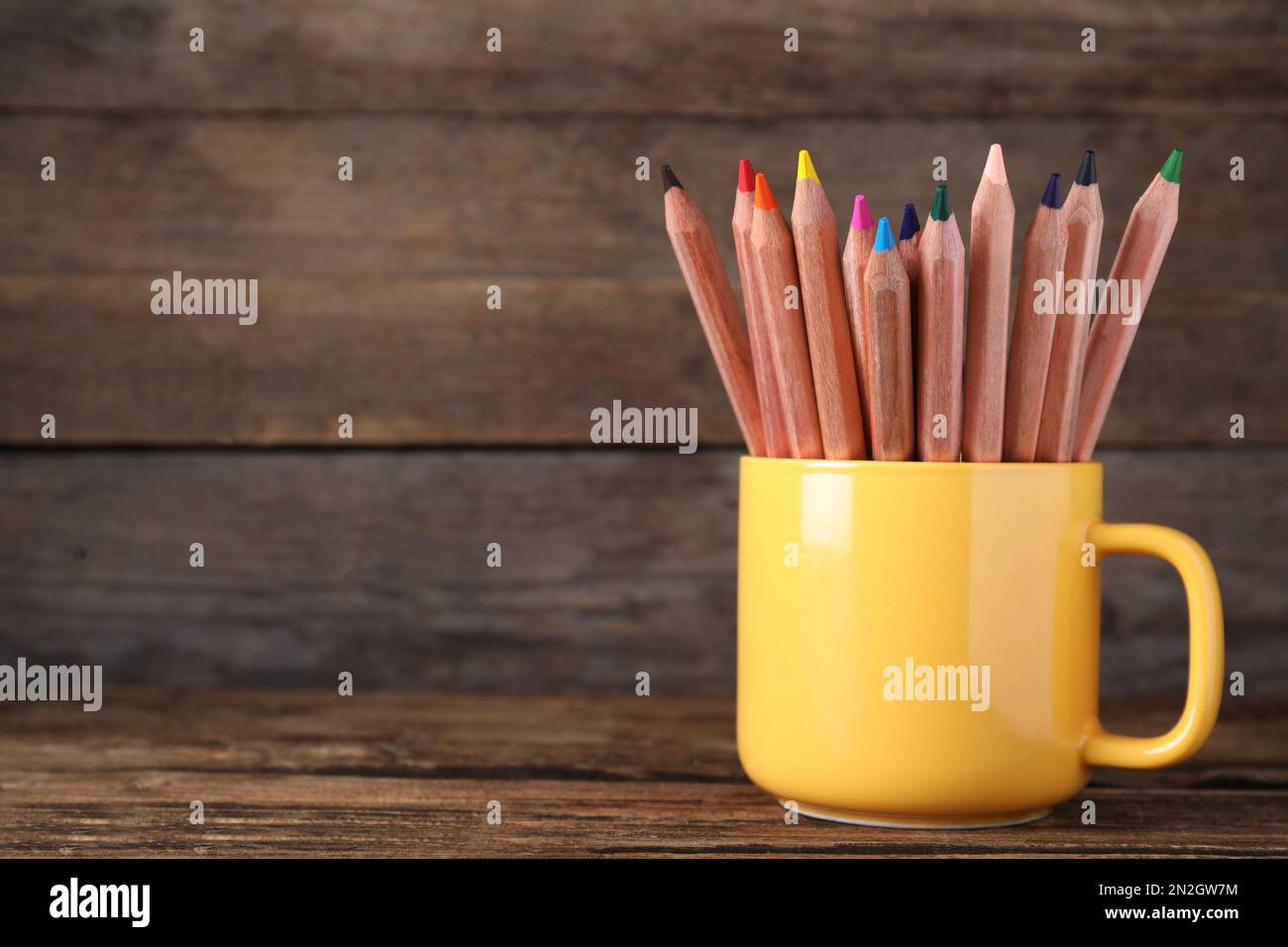 Colorful pencils in cup on wooden table. Space for text Stock Photo