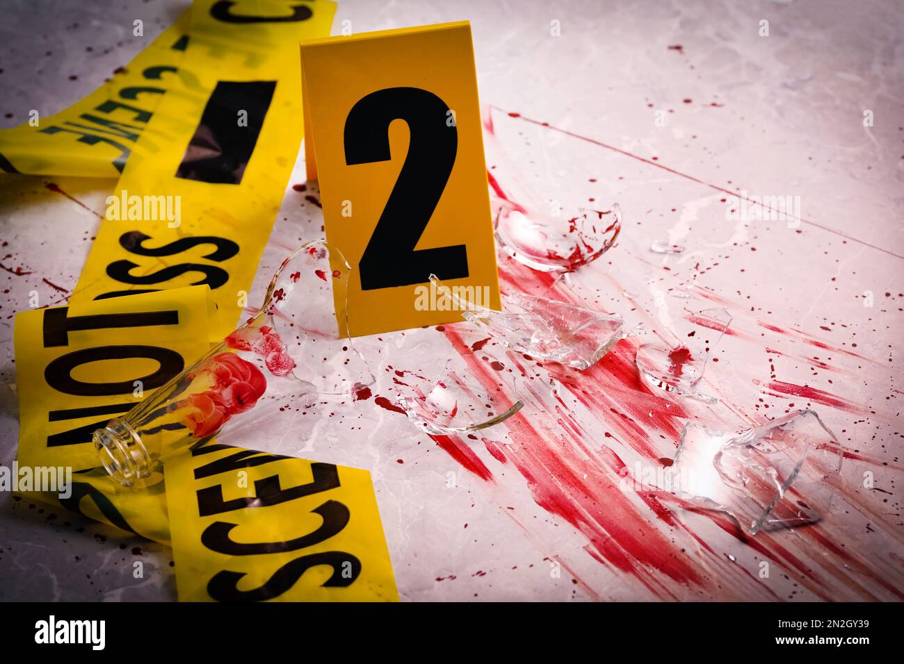 Yellow tape, crime scene marker and smithereens in blood on marble table, closeup Stock Photo