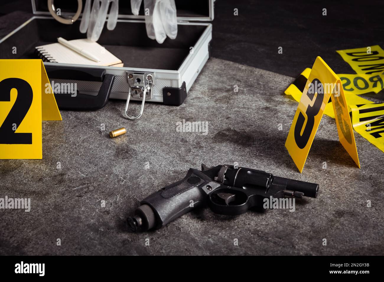 Shell casing, gun and crime scene marker on grey stone table Stock ...