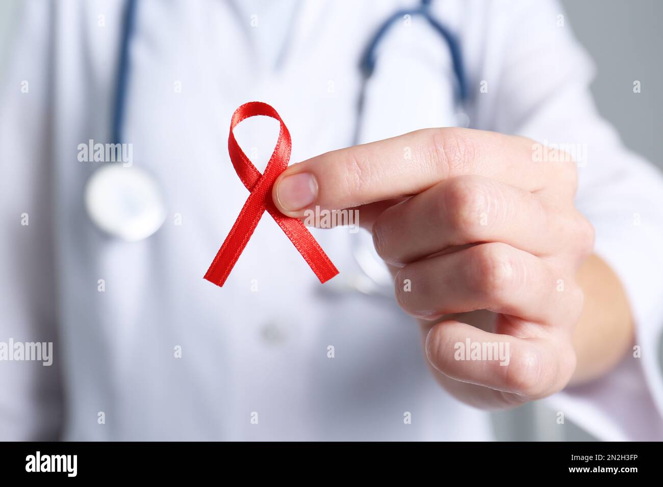 Doctor holding red awareness ribbon, closeup. World AIDS disease day Stock Photo