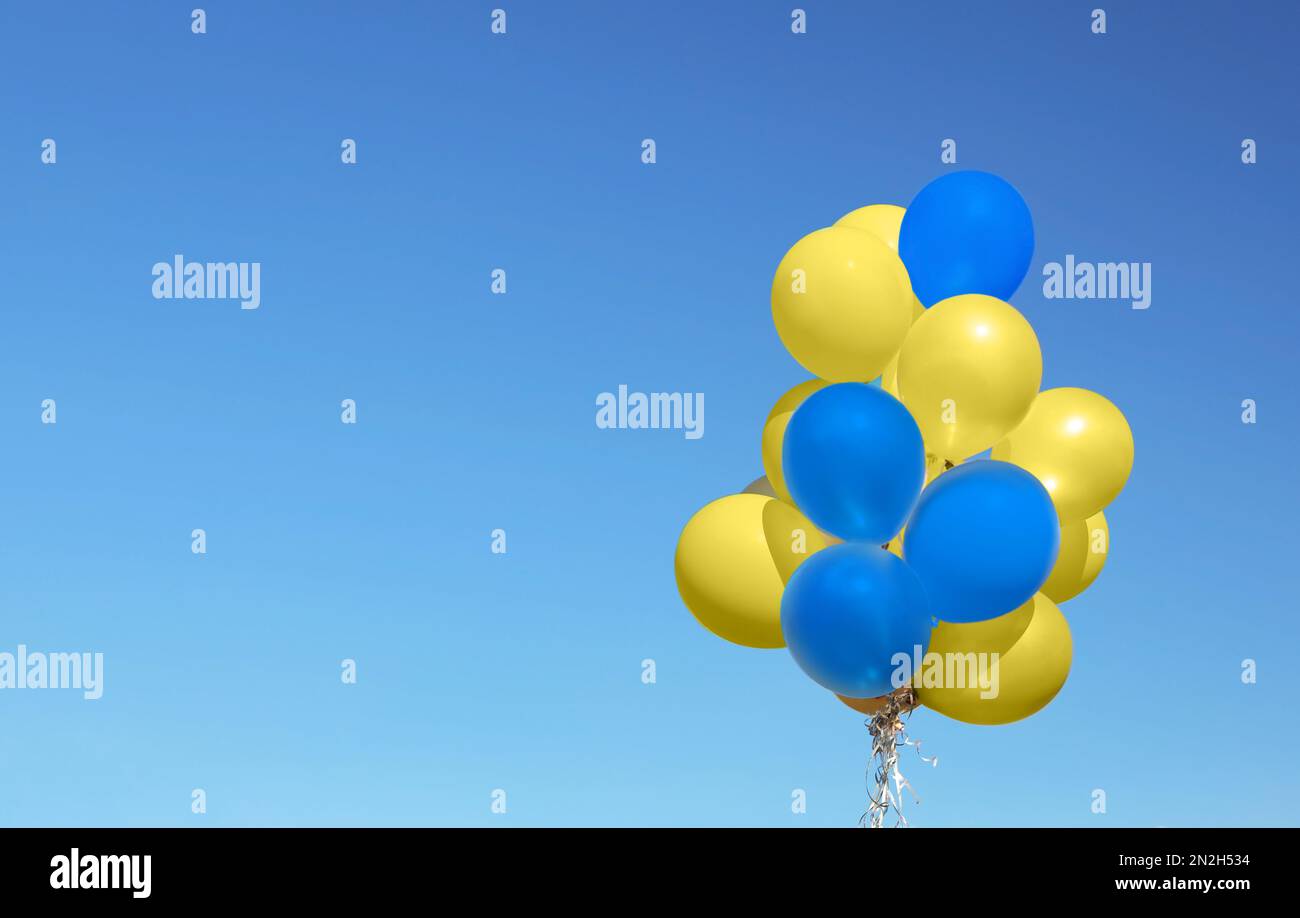Many balloons in colors of Ukrainian flag against blue sky. Space for text Stock Photo