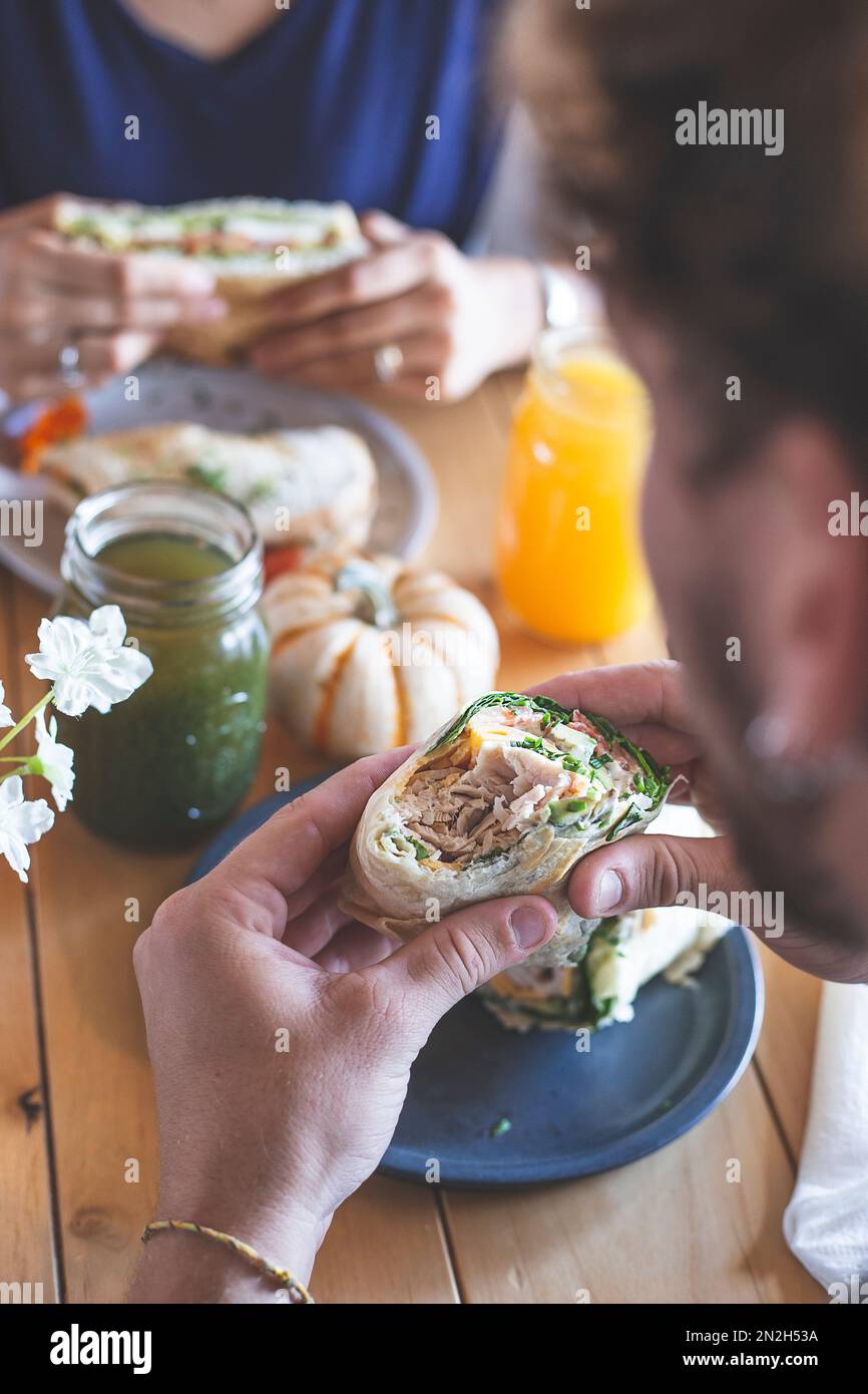 Male and female couple eating in a restaurant. Wrap and sandwich with natural juices. Healthy