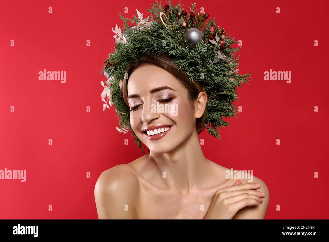 Beautiful young woman wearing Christmas wreath on red background Stock Photo