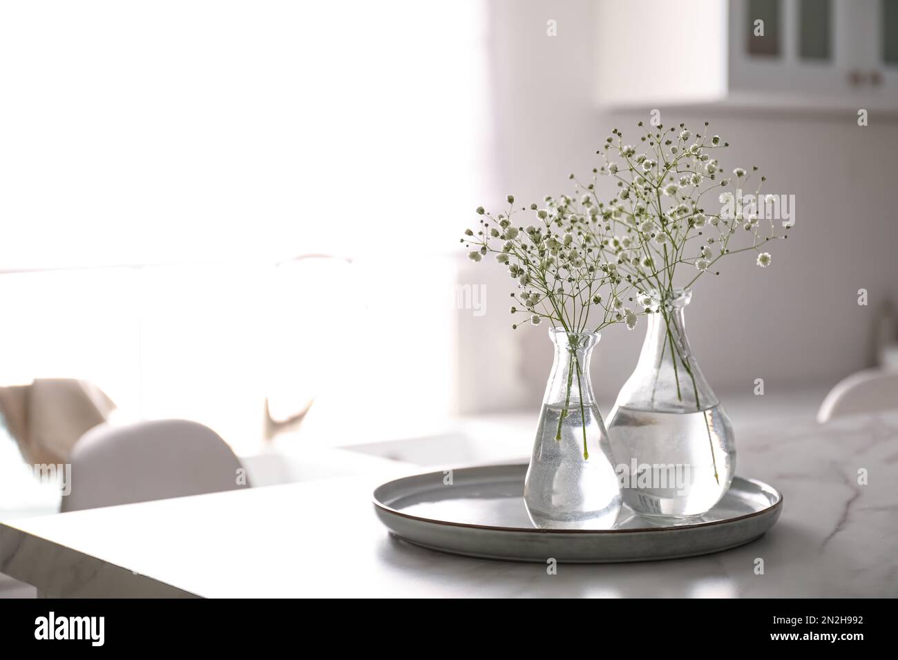 Vases with gypsophila flowers on table in kitchen, space for text ...