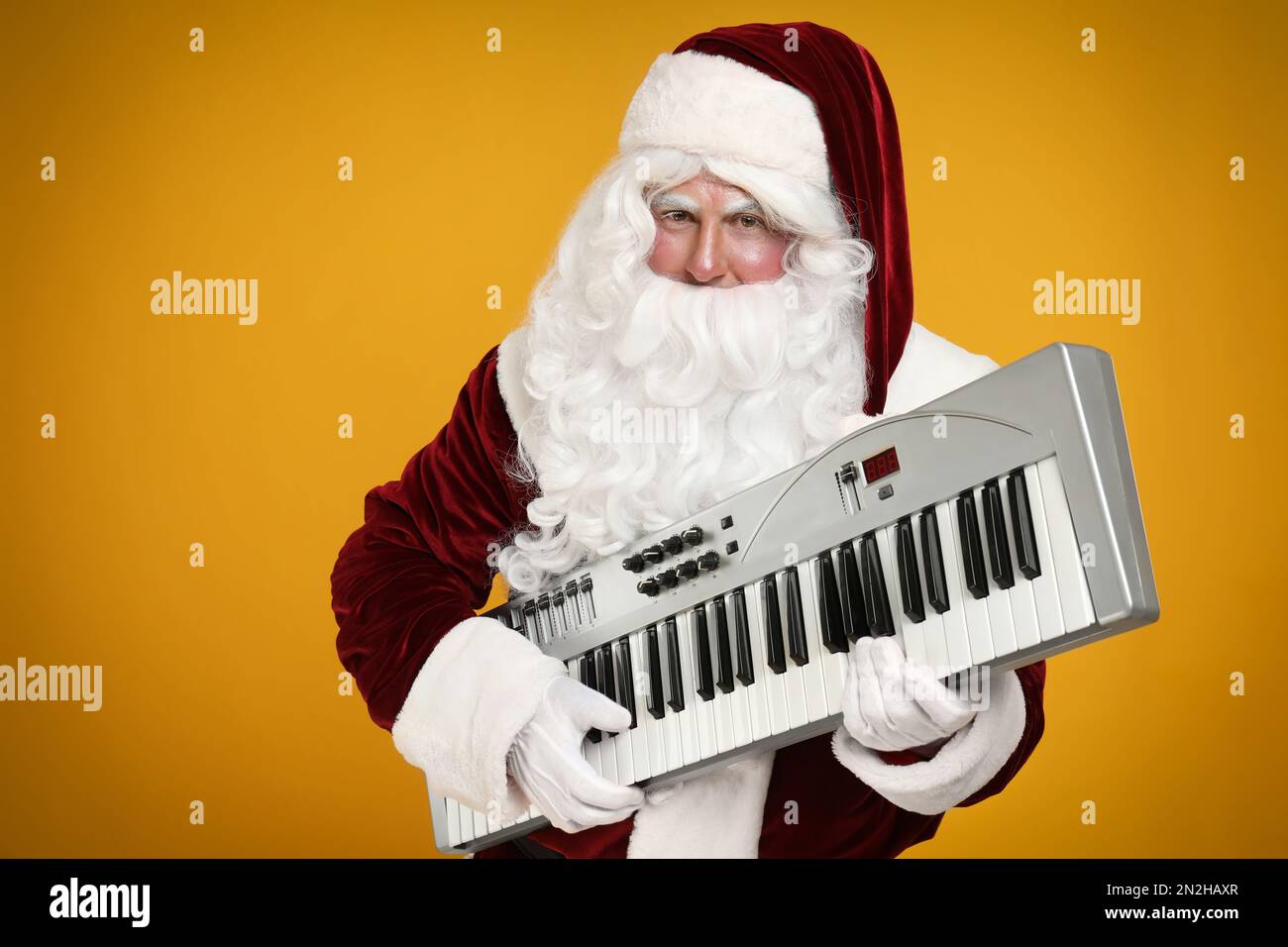 Santa Claus with synthesizer on yellow background. Christmas music