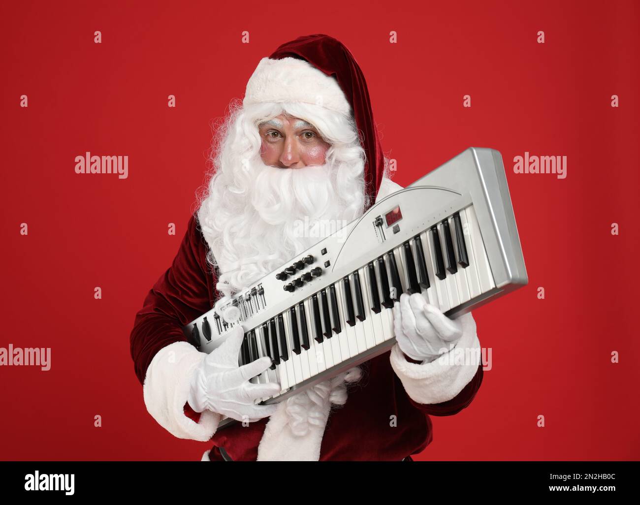 Santa Claus with synthesizer on red background. Christmas music Stock