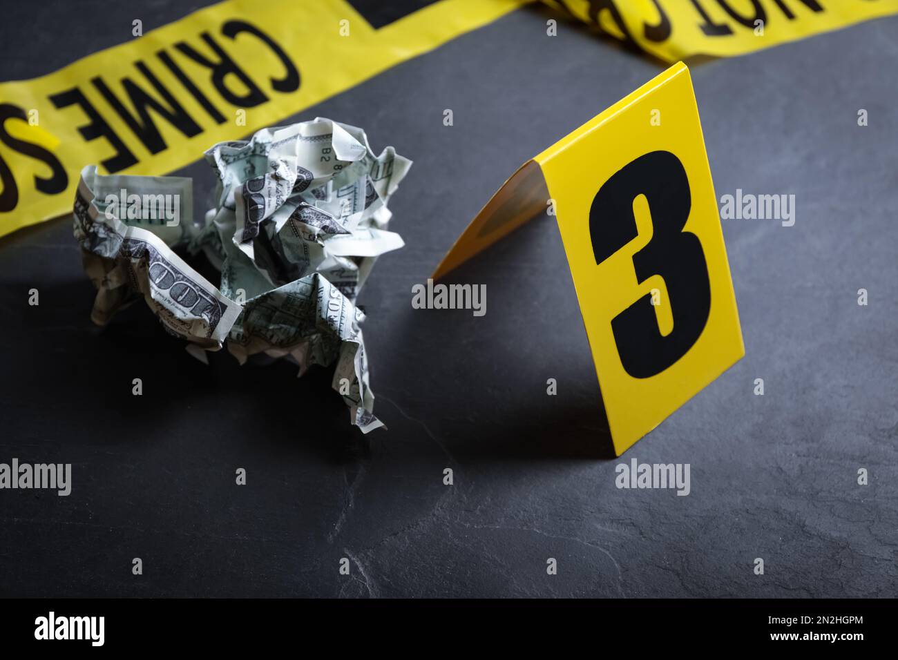 Crime scene marker and crumpled dollars on black slate table, closeup ...