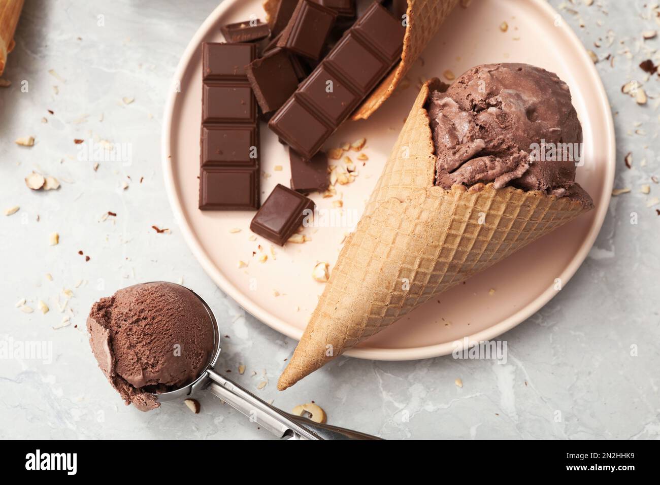 https://c8.alamy.com/comp/2N2HHK9/delicious-ice-cream-in-wafer-cone-and-chocolate-pieces-on-light-grey-table-flat-lay-2N2HHK9.jpg