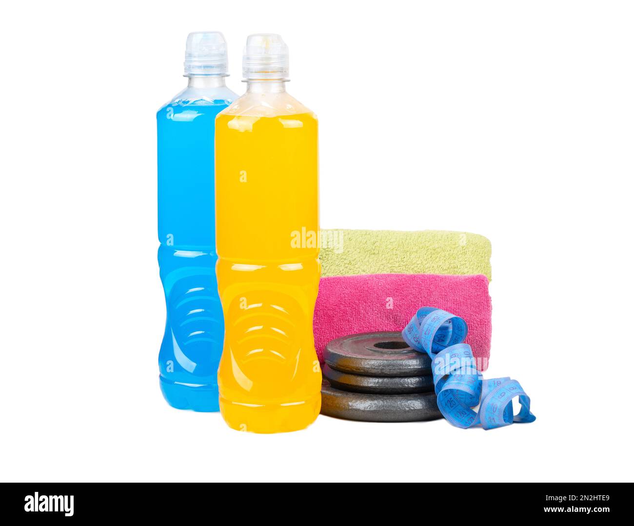 Plastic bottles with blue and orange isotonic drinks with dumbbell pancakes, a measuring centimeter and two towels on a white background. Stock Photo