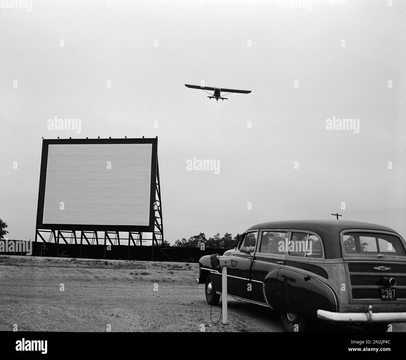 A plane comes in for a landing over the movie screen at the FlyIn