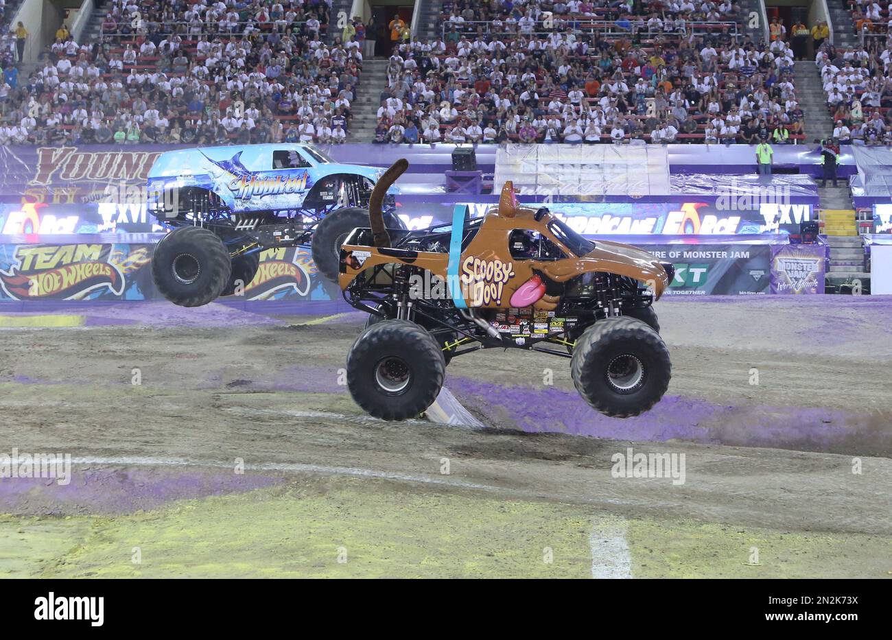 Fans watch as monster truck, Hooked, left, and ScoobyDoo, race to the
