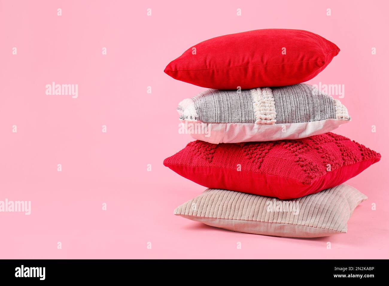 Stack of decorative pillows on pink background Stock Photo