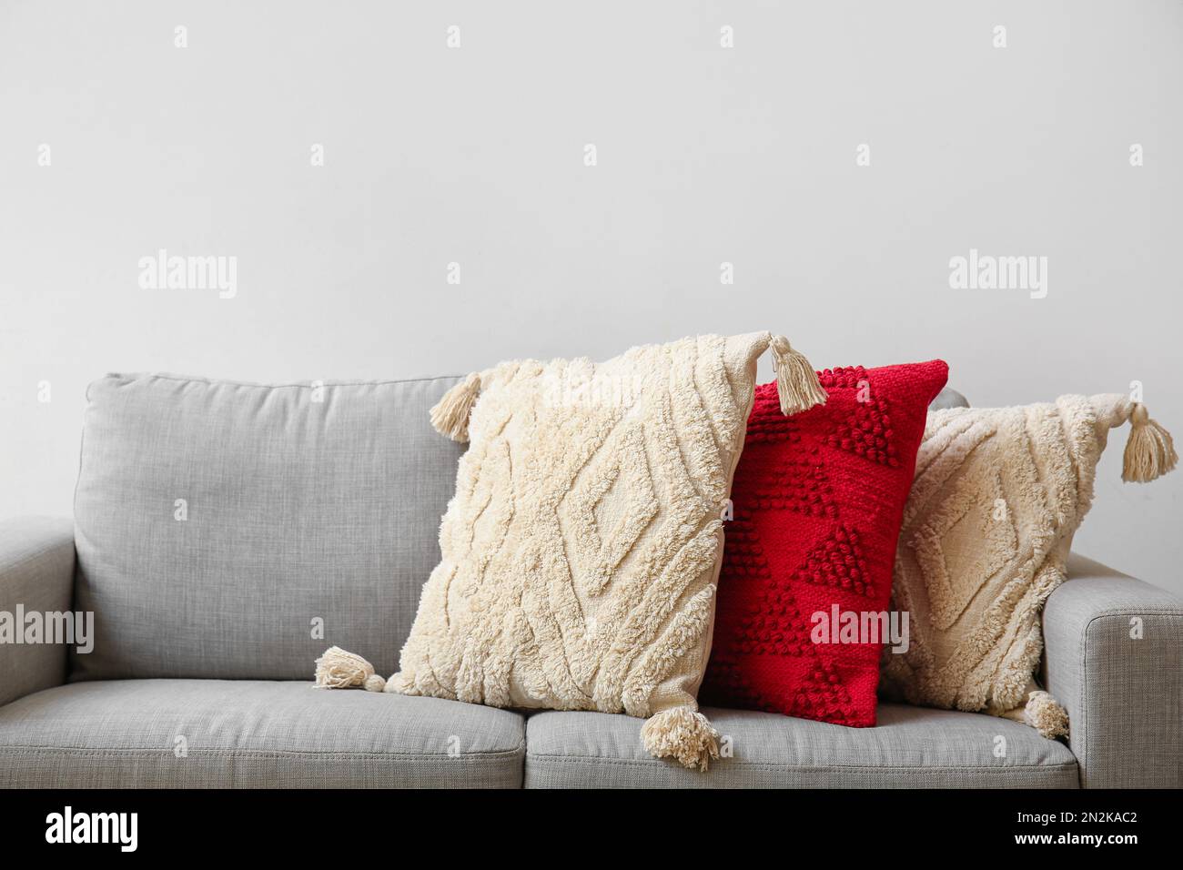 Decorative pillows on sofa near light wall, closeup Stock Photo