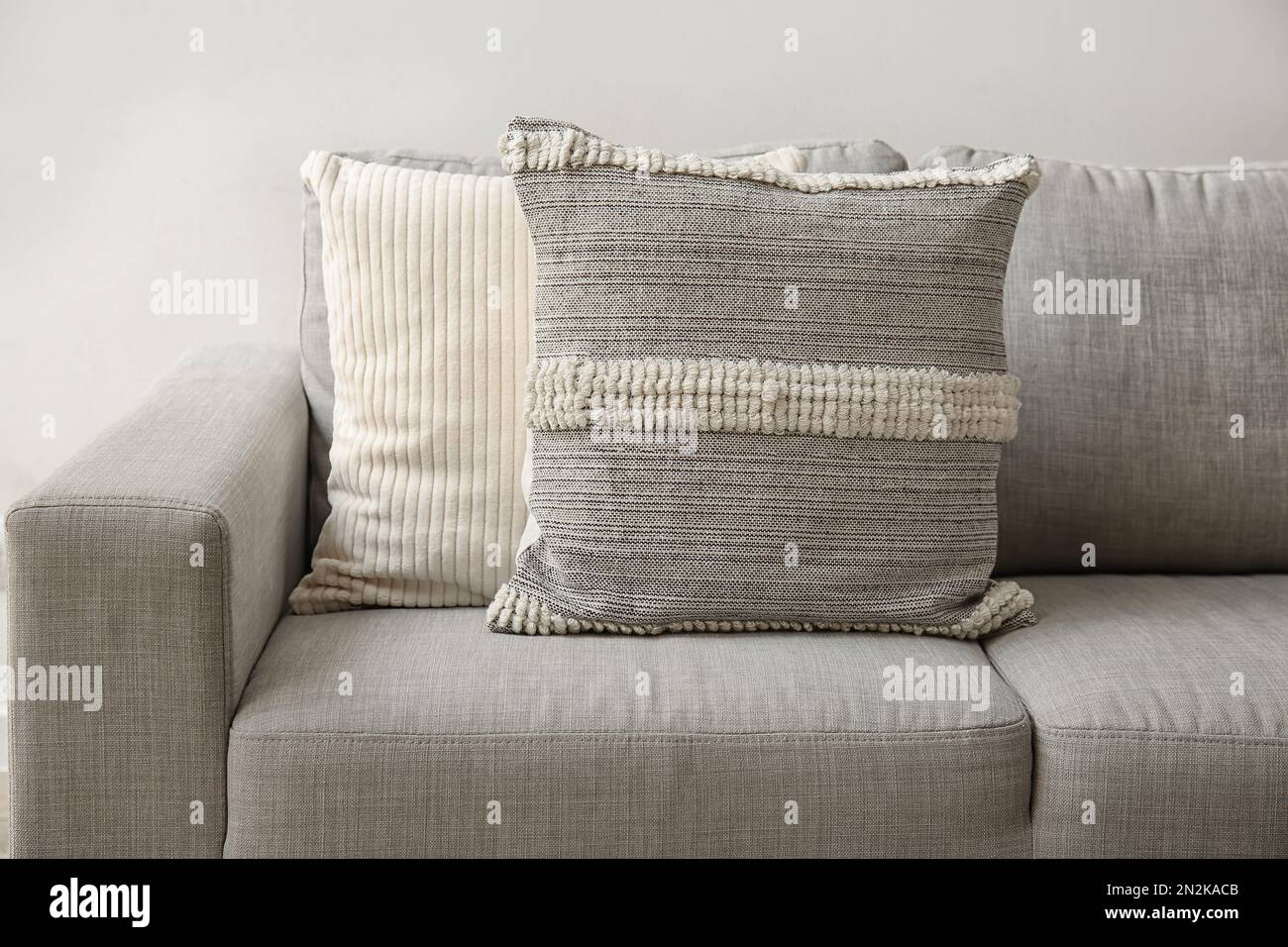 Decorative pillows on sofa near light wall, closeup Stock Photo