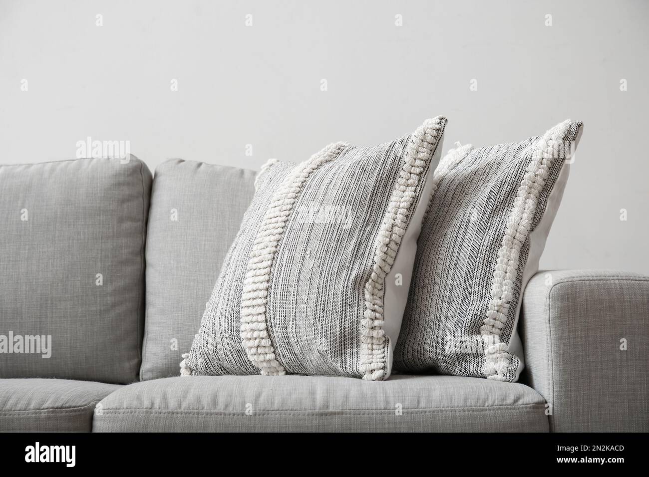 Soft pillows on sofa near light wall, closeup Stock Photo