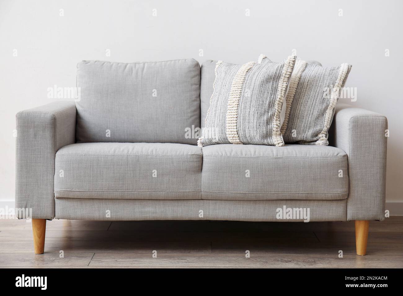 Soft pillows on sofa near light wall Stock Photo