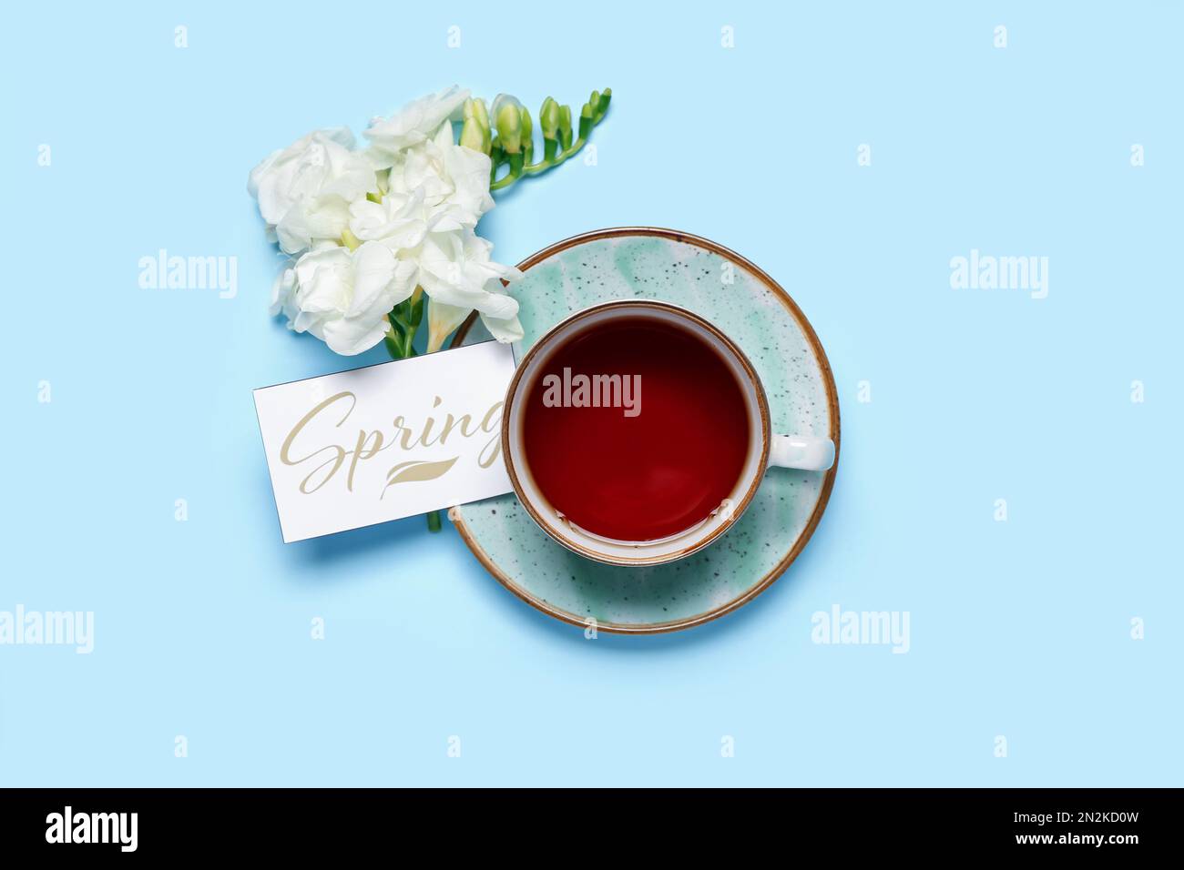 Cup of tea, freesia flowers and card with word SPRING on color ...