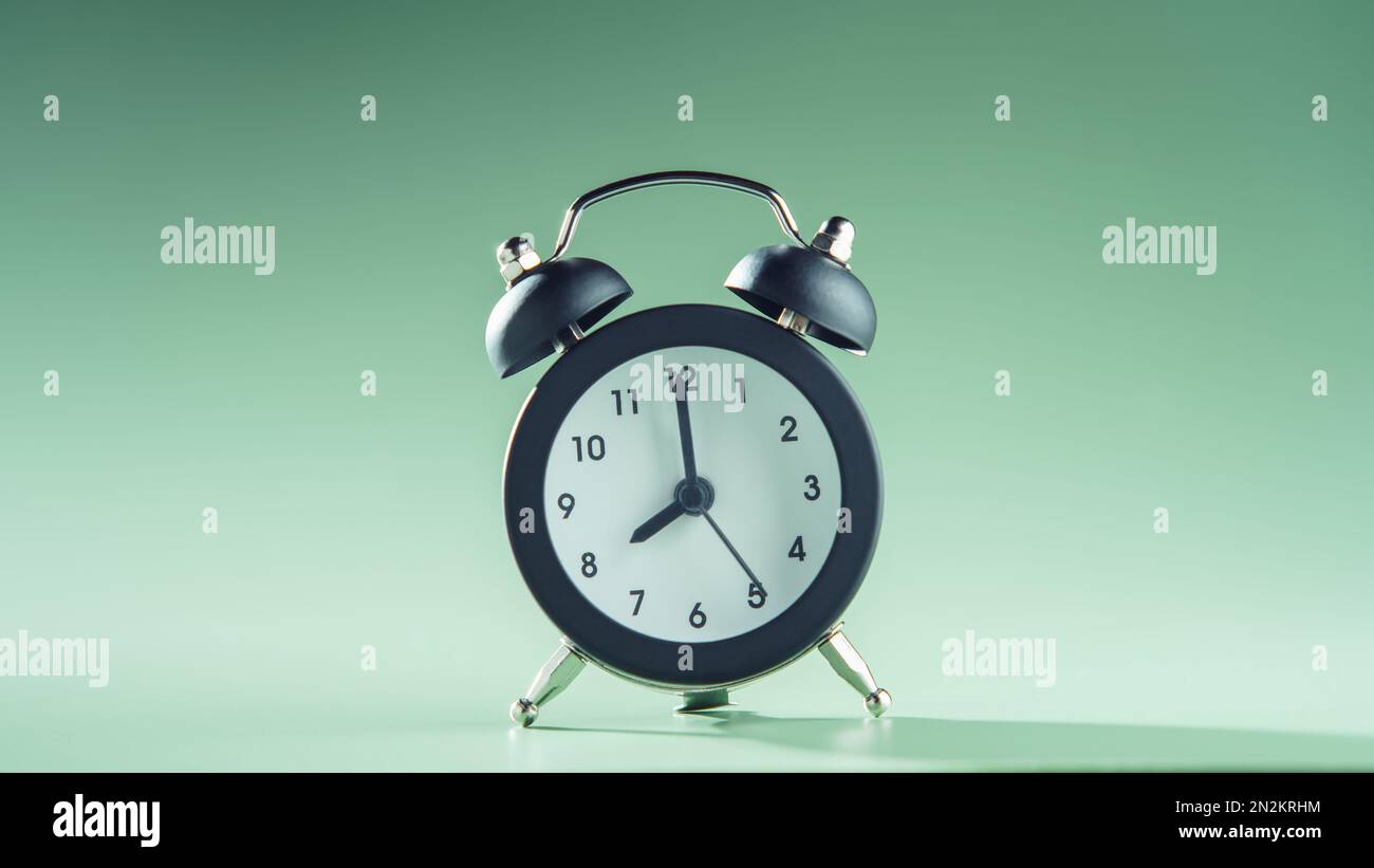Blue clock showing eight o'clock on green background. Time, timetable