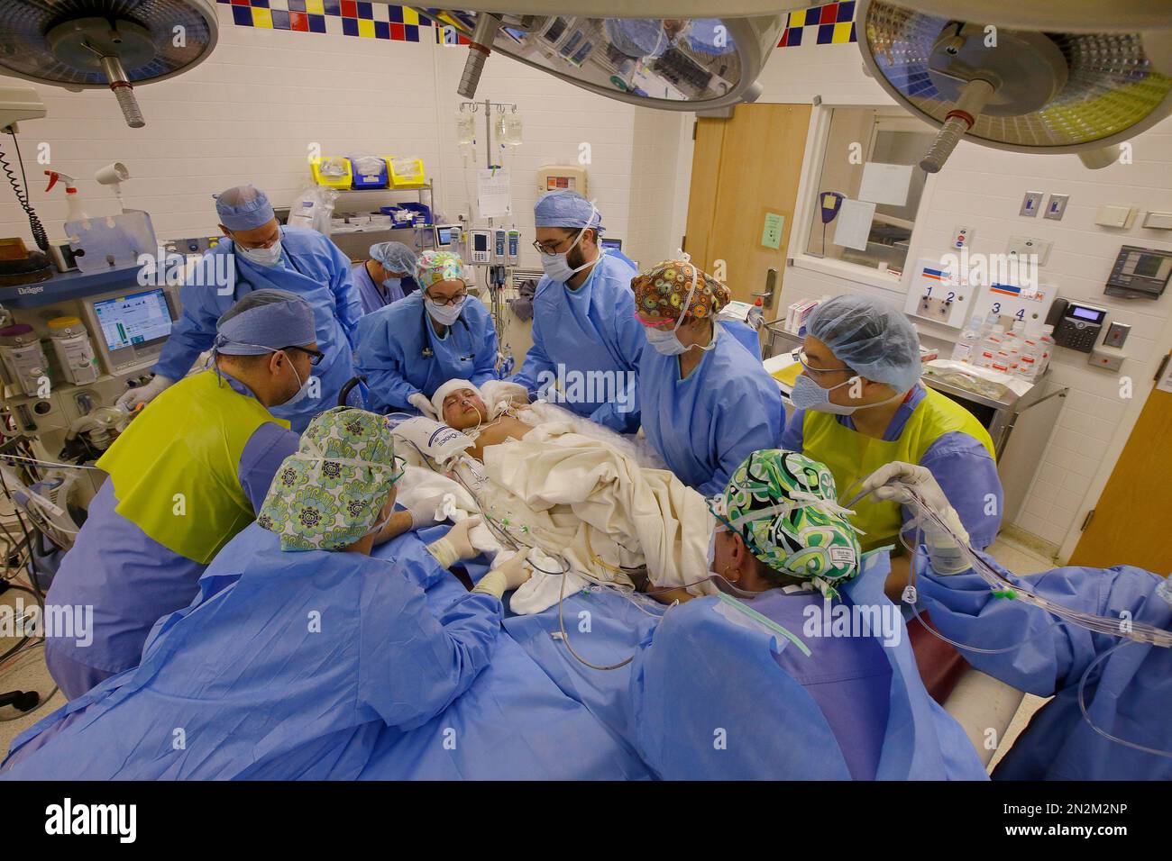 In this Friday, March 13, 2015 photo members of the operating room team  lift Paola Matute Porter, 9, off of her bed and onto the operating table  before beginning a more than