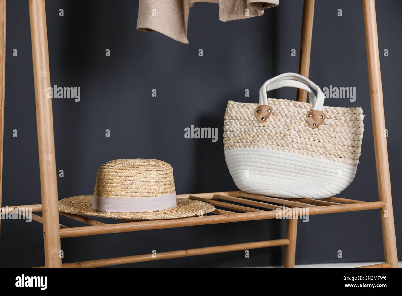 Straw hat and bag on clothing rack indoors Stock Photo - Alamy
