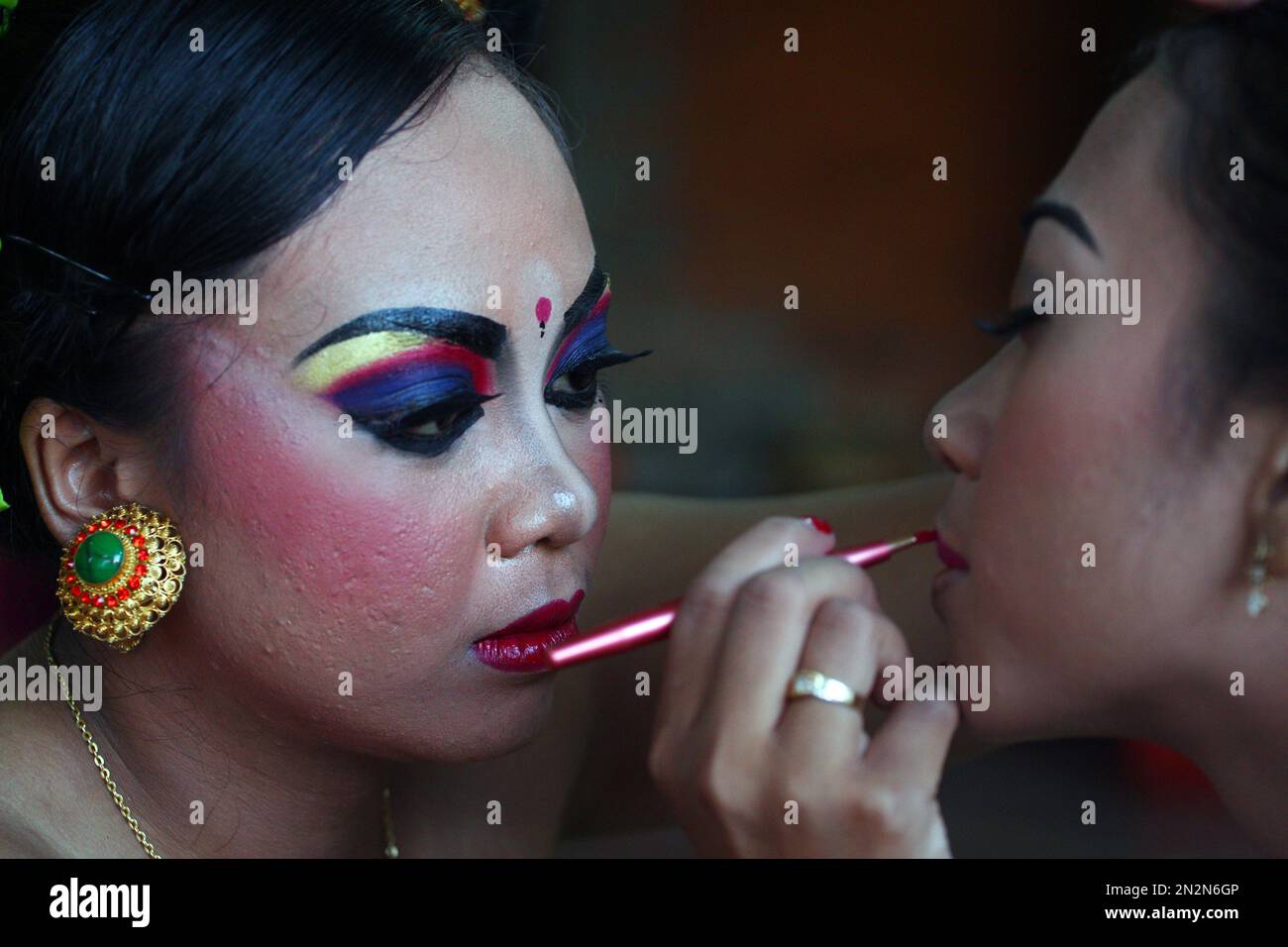 Balinese girl applies makeup to Hindu dancer as they prepare for a performance during a to celebrate Nyepi, Day of Silence that marks Balinese Hindu's New Year Bali, Indonesia,